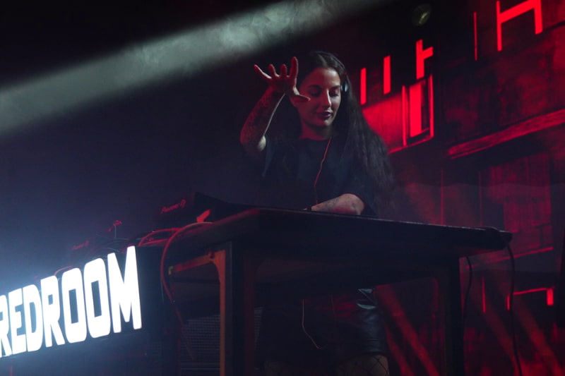 High-energy DJ performance with dramatic red mood lighting and stage effects